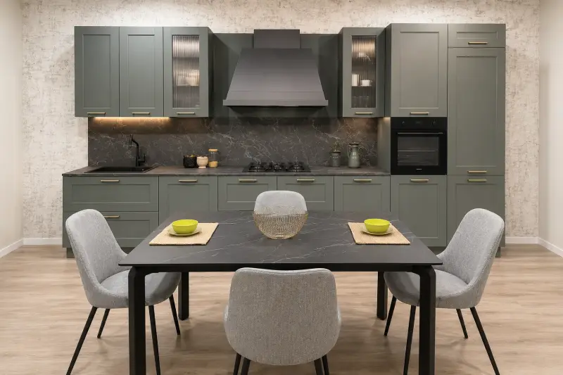 Cucina Classic Grey Elegance: mobili grigi con ante lavorate, cappa importante e piano effetto marmo.