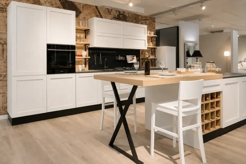 Cucina Eleganza Nordica: ante bianche e isola con piano in legno naturale e gambe nere a X a contrasto.