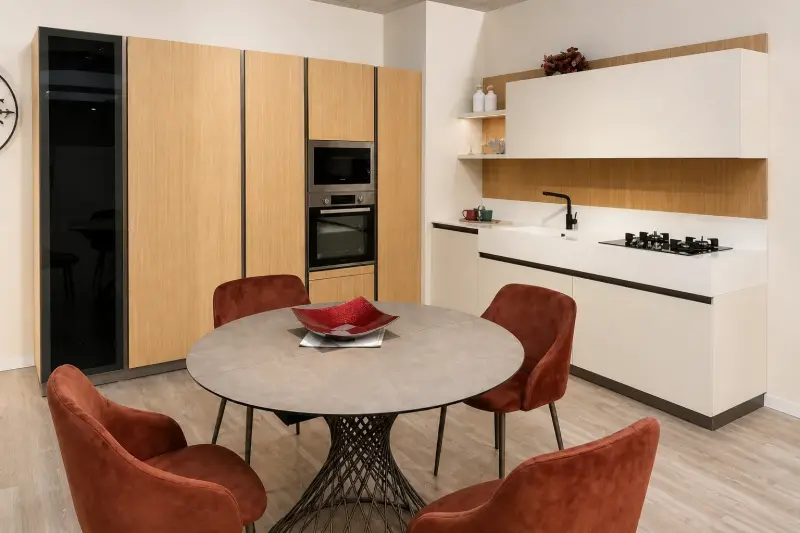 Cucina Natural Harmony: colonne in legno chiaro, basi bianche e tavolo rotondo per la zona pranzo.