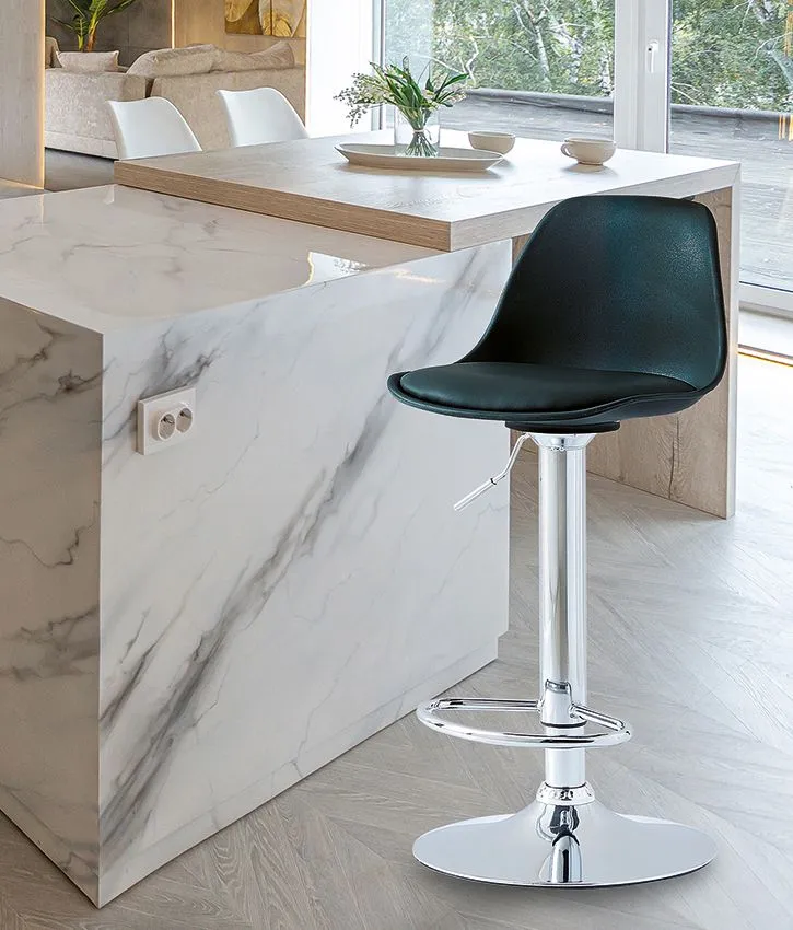 Sgabello nero da bar accanto a un'isola cucina in marmo bianco in un luminoso interno moderno.