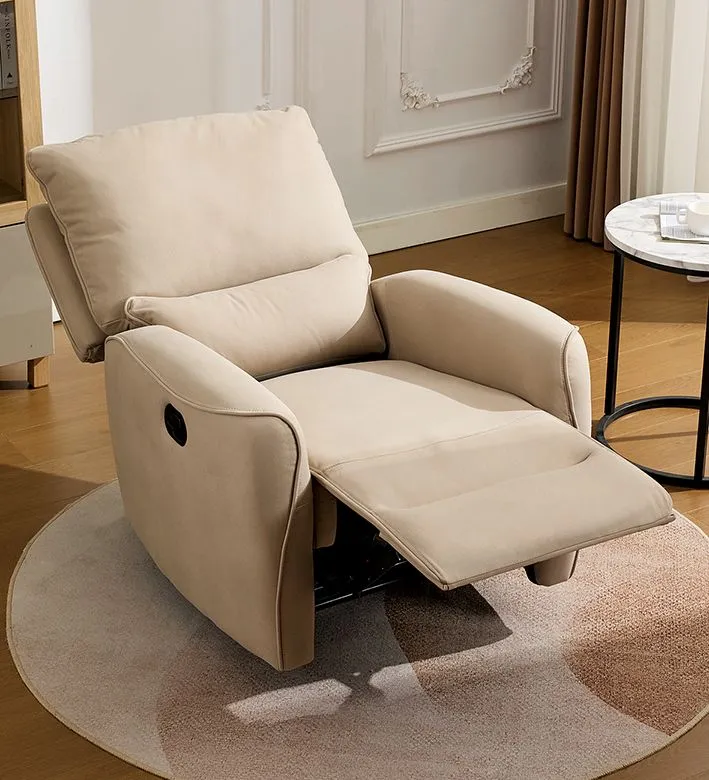 Poltrona reclinabile beige con poggiapiedi su un tappeto rotondo in soggiorno, accanto a un tavolino.