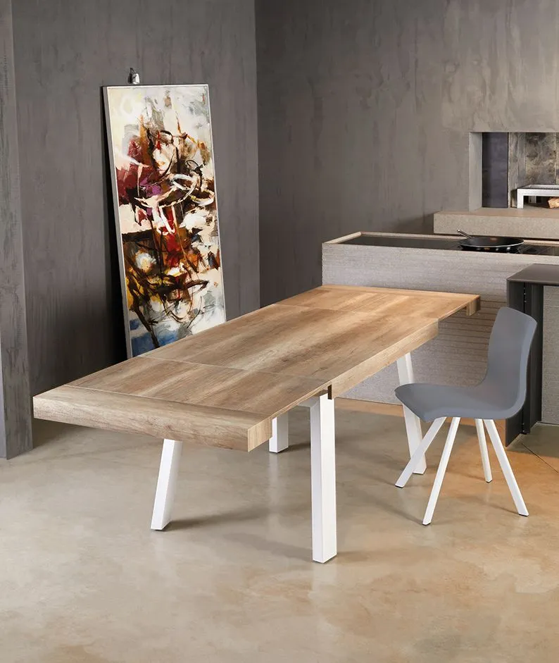 Sala da pranzo moderna con tavolo in legno chiaro, sedie bianche, pareti grigie e quadri astratti.