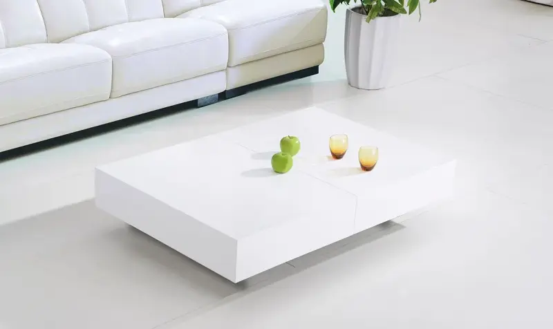 Soggiorno minimalista bianco con tavolino basso bianco e piccolo centrotavola di frutta.